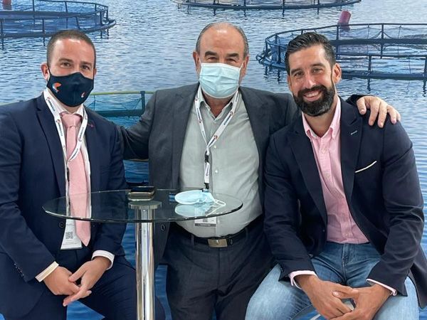 Tres hombres con máscaras faciales posan para una fotografía.