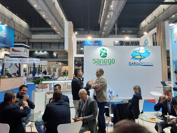 Un grupo de personas están sentadas alrededor de mesas en una convención.