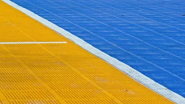 Una cancha de baloncesto azul y amarilla con una línea blanca.