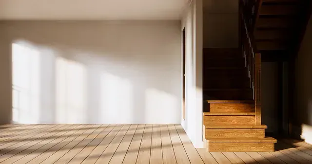 Una habitación vacía con suelo de madera y escaleras.