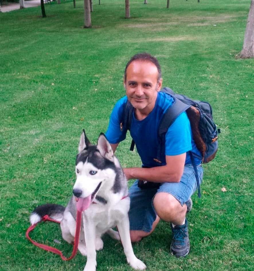Un hombre está arrodillado junto a un perro husky.