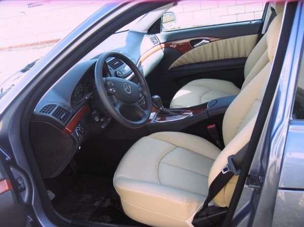 El interior de un coche con asientos y volante de color beige.