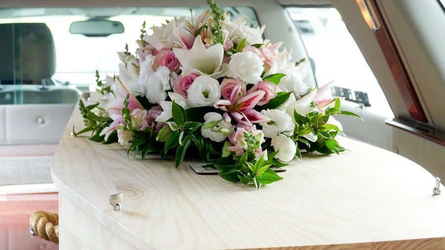 Un ataúd con flores encima está en una limusina.