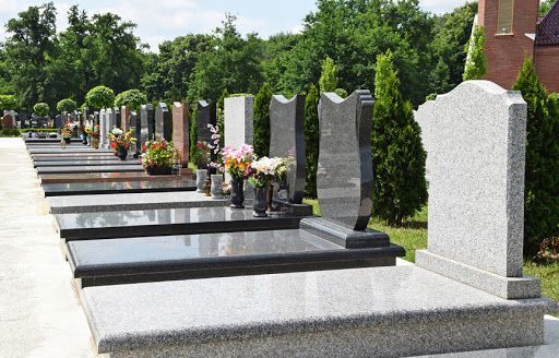Una hilera de tumbas en un cementerio con flores en ellas.