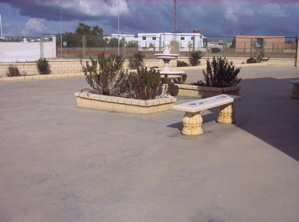 Un patio de hormigón con jardineras y un banco.