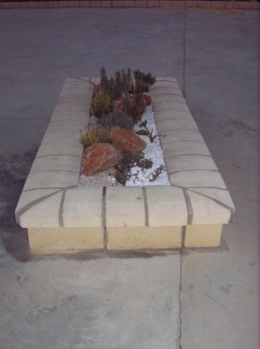 Un banco de hormigón con rocas y plantas.