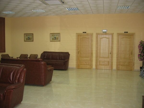 Una sala de estar con un sofá y sillas y tres puertas.