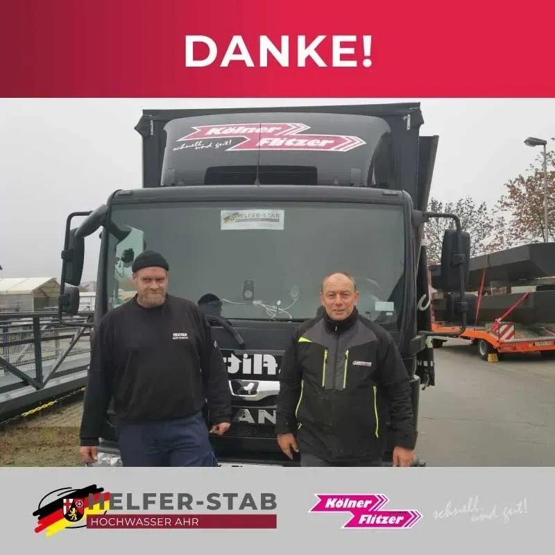 Zwei Männer stehen vor einem schwarzen Lastwagen mit dem Schriftzug „Danke!“ darüber und Firmenlogos darunter.