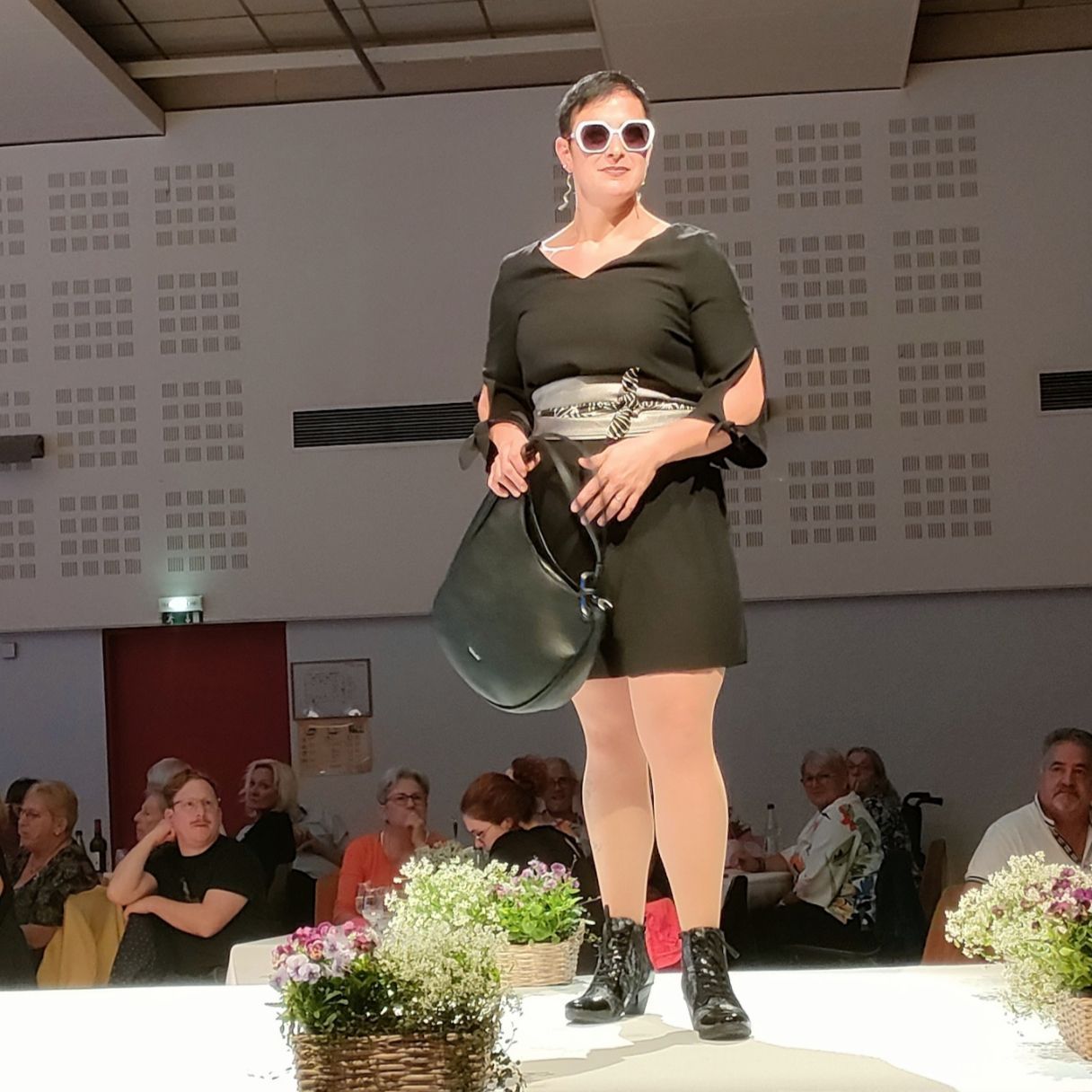 Femme qui défile avec un sac vert et des lunettes