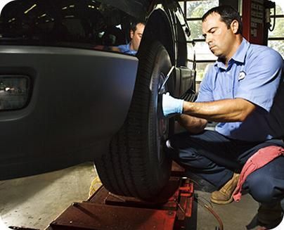 Un hombre con camisa azul está trabajando en un neumático de automóvil.
