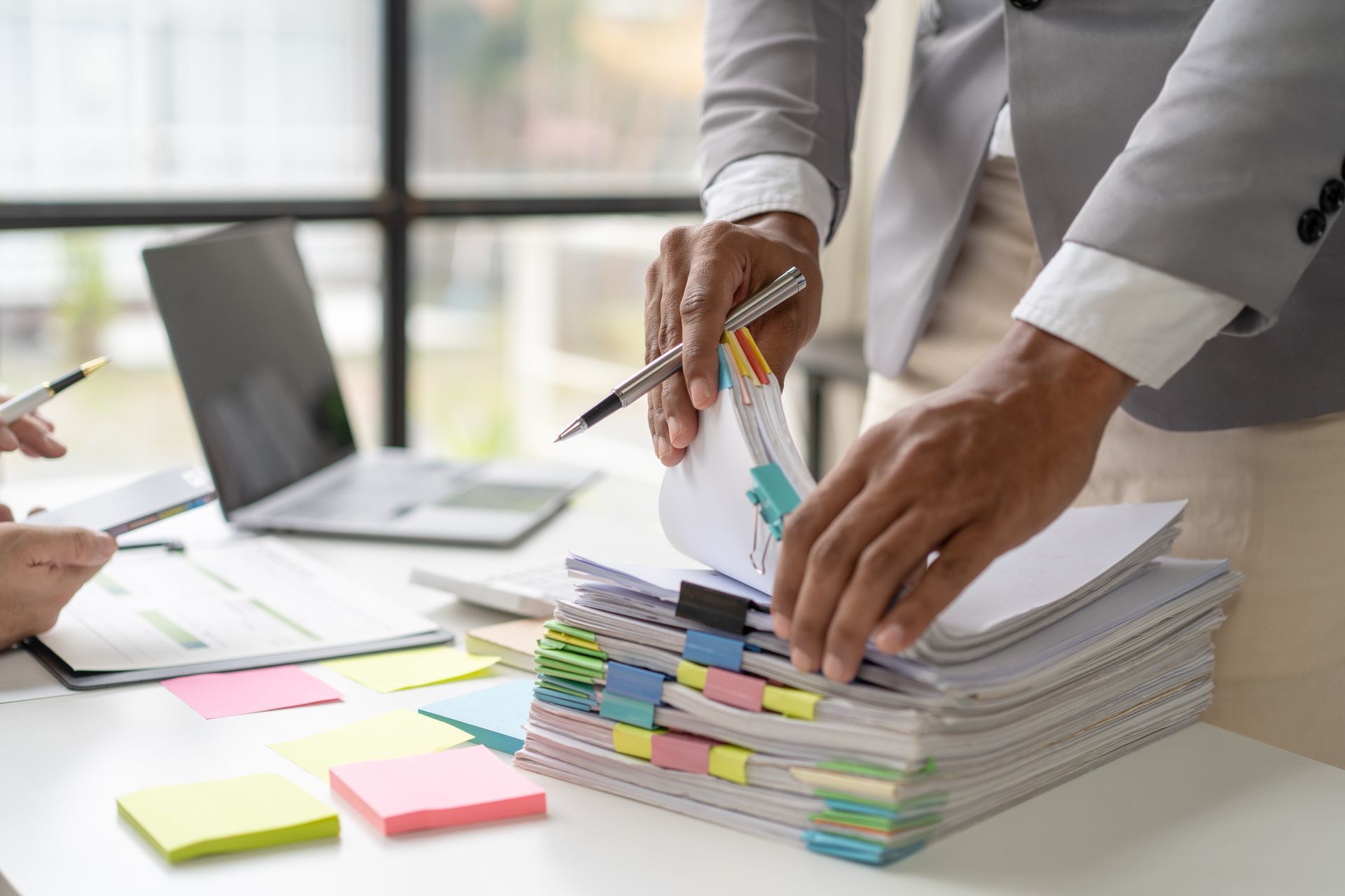 Mains qui trient des dossiers avec de nombreux post-it