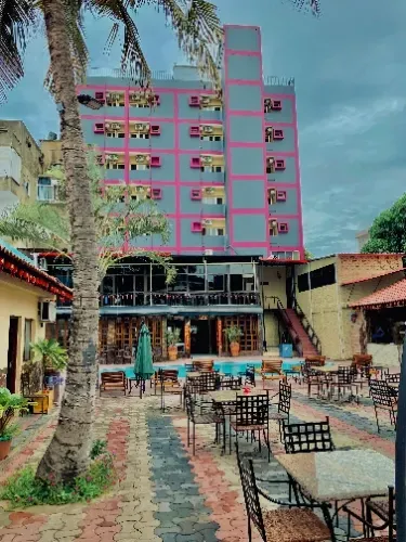 Um grande edifício com mesas e cadeiras na frente.