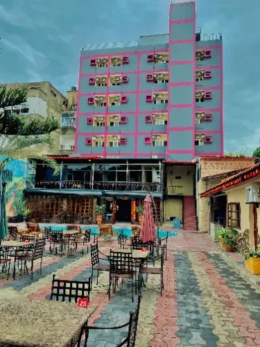 Um grande edifício com mesas e cadeiras na frente.