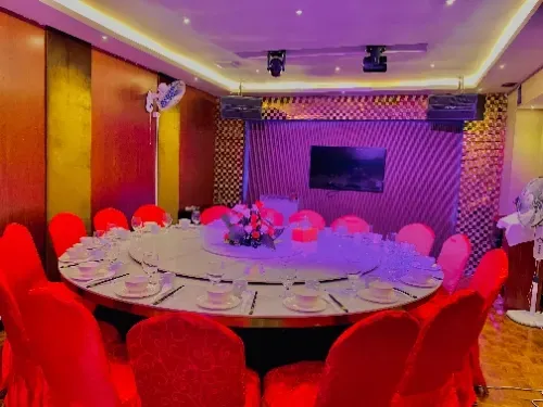 Uma grande sala de jantar com uma mesa redonda e cadeiras vermelhas.