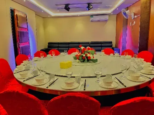 Uma grande sala de jantar com uma mesa redonda e cadeiras vermelhas.