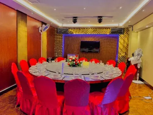 A large dining room with a round table and red chairs.