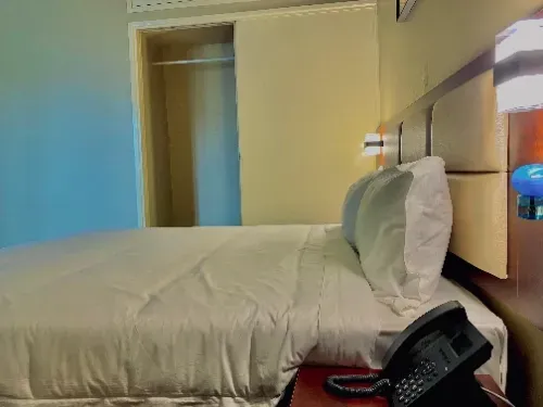 A hotel room with a bed and a phone on the nightstand.