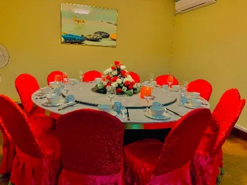 Uma sala de jantar com uma mesa redonda e cadeiras vermelhas.