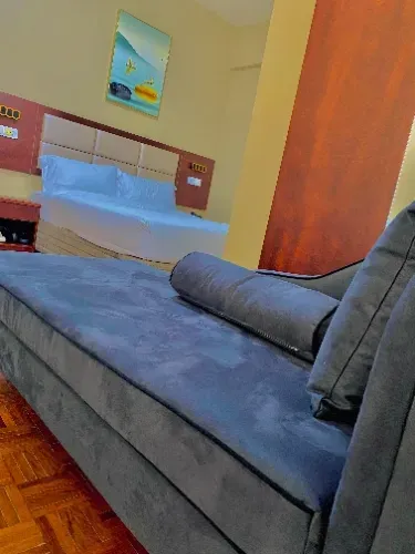 Um sofá está sentado em um quarto de hotel ao lado de uma cama.