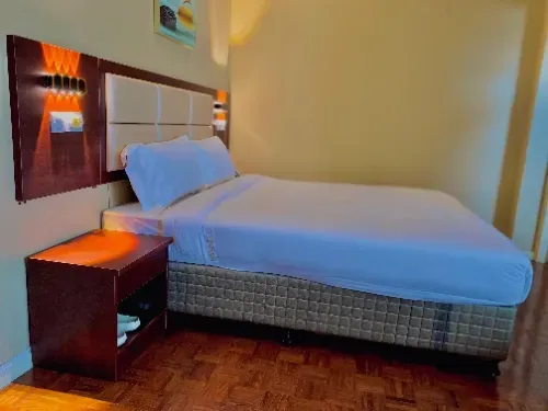 A hotel room with a bed and a nightstand