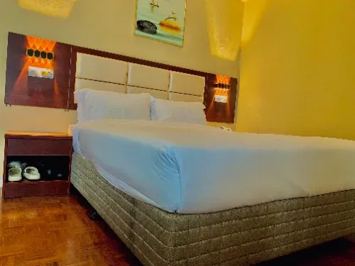 A hotel room with a king size bed and a nightstand.