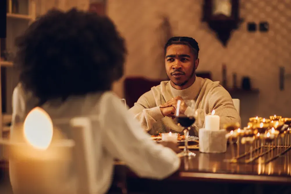 Um homem e uma mulher estão sentados à mesa bebendo vinho.