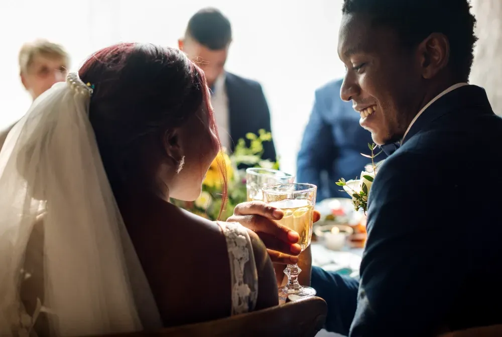 Uma noiva e um noivo estão sentados à mesa com copos de cerveja.