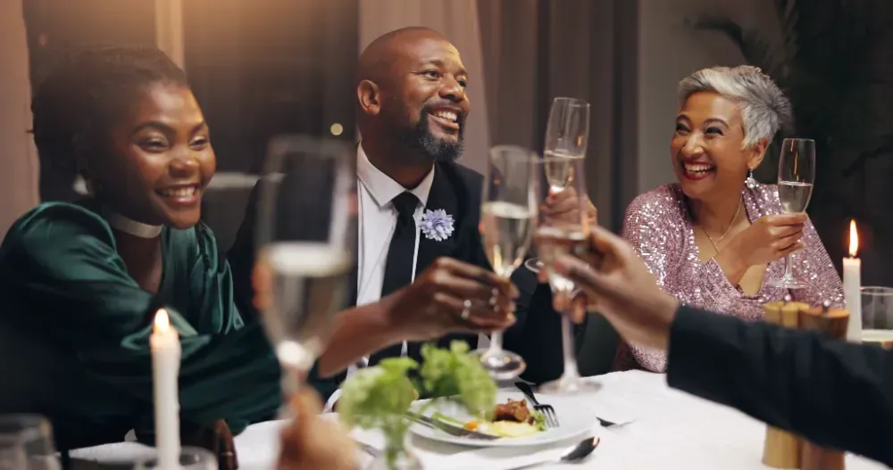 A group of people are sitting at a table toasting with champagne glasses.