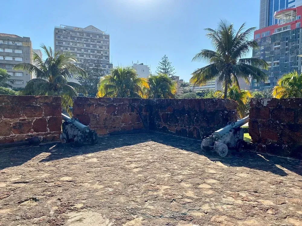 Dois canhões estão posicionados em frente a um muro de pedra.