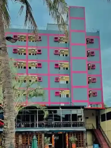 Um grande edifício com mesas e cadeiras na frente.