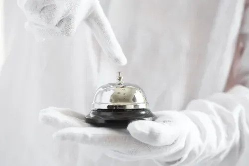 A person wearing white gloves is holding a bell in their hand.