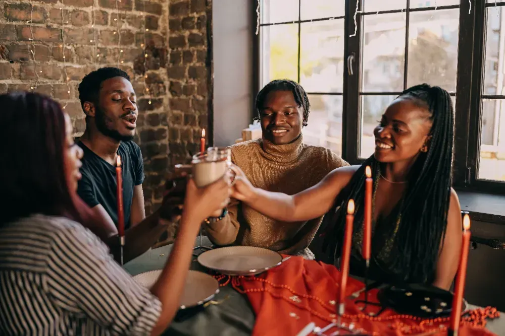 Um grupo de pessoas está sentado à mesa brindando com bebidas.