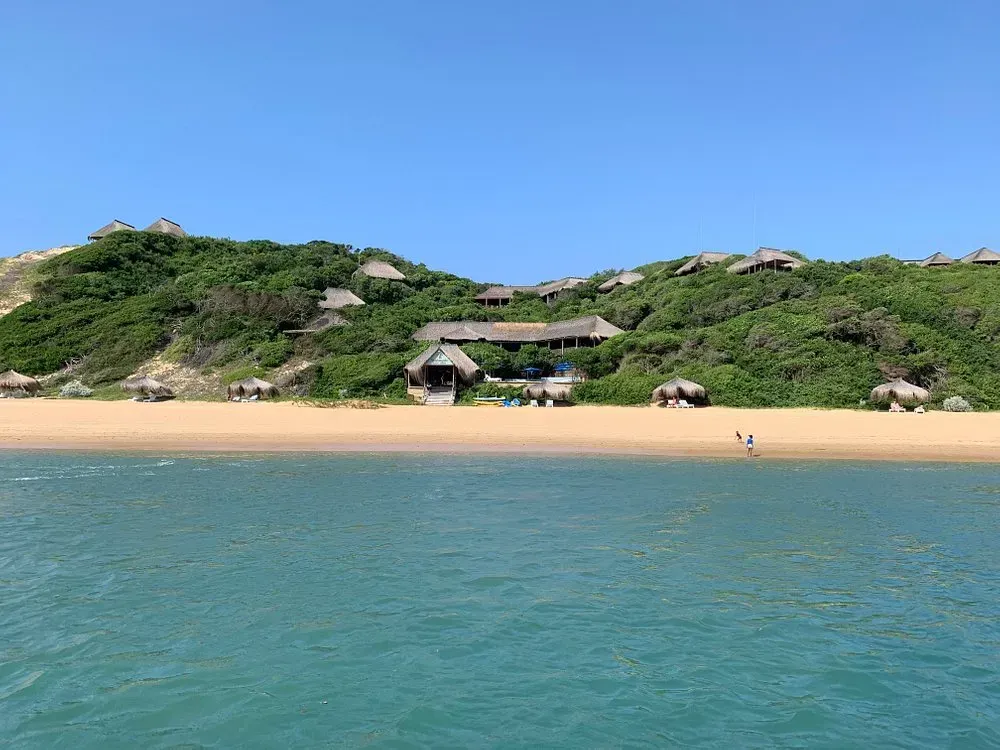 A view of a beach from the water with a house in the background.