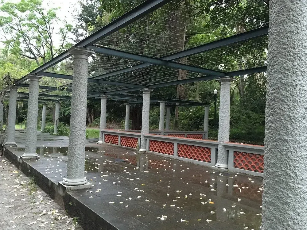 Uma fileira de colunas em um parque com árvores ao fundo