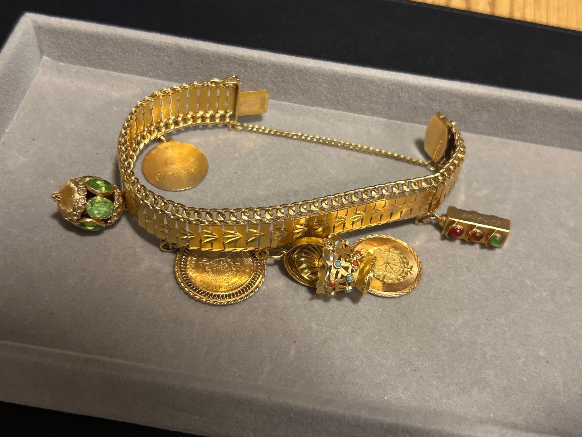 Juego de joyas de oro con pulsera, anillos y pendientes en una bandeja gris