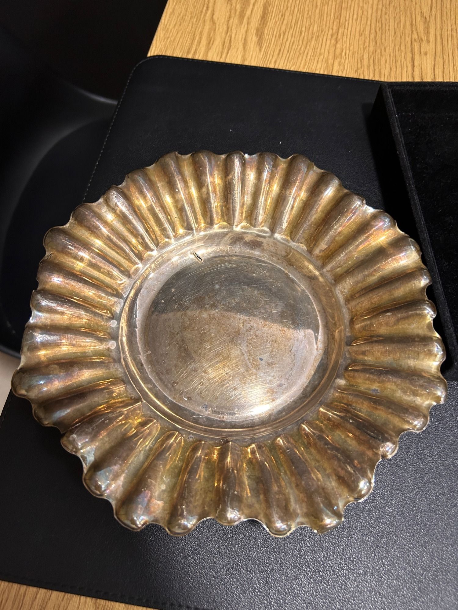 Cenicero metálico estriado en tono dorado sobre una superficie oscura