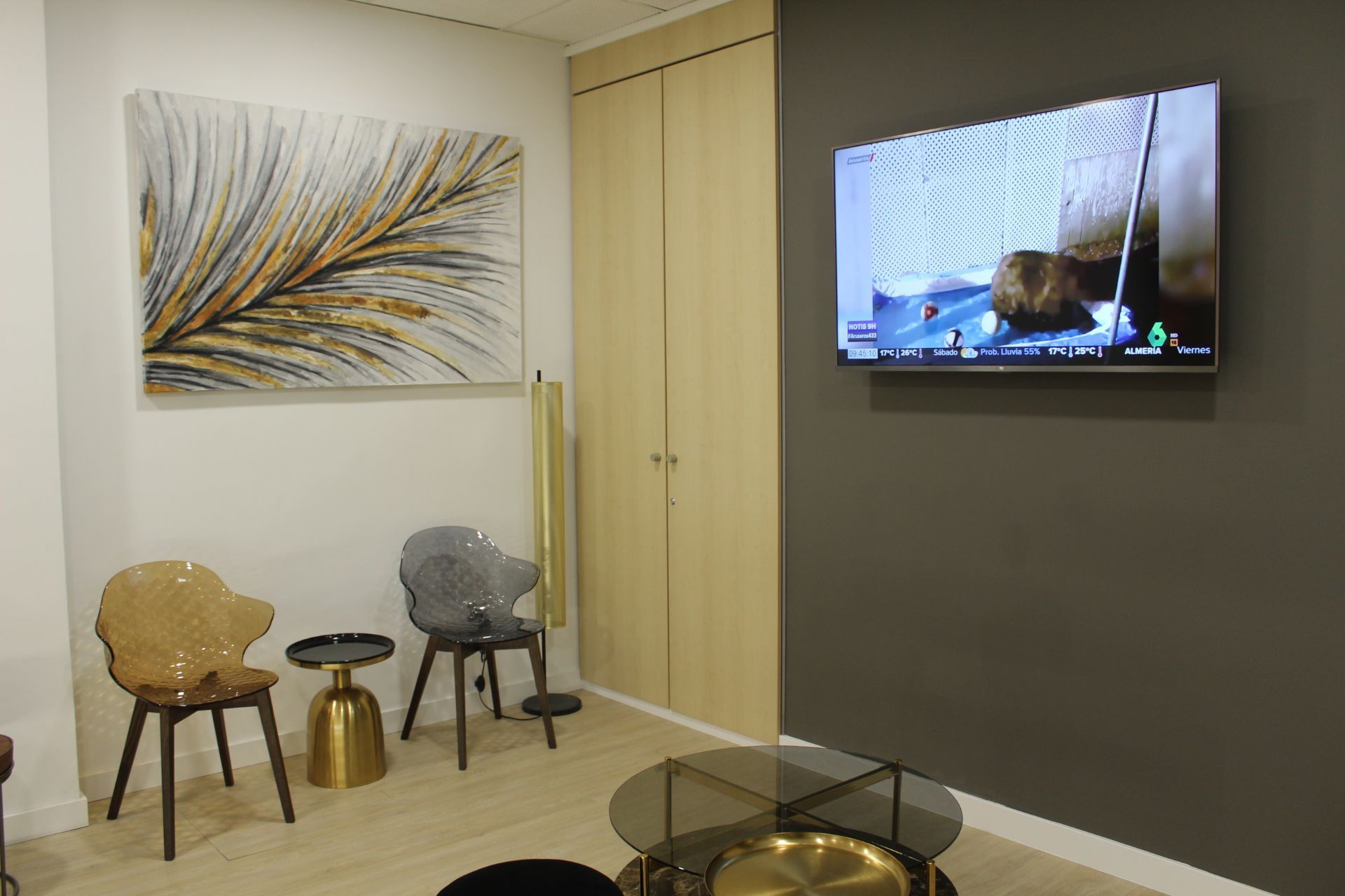 Una sala de estar con sillas, mesas y un televisor de pantalla plana en la pared.