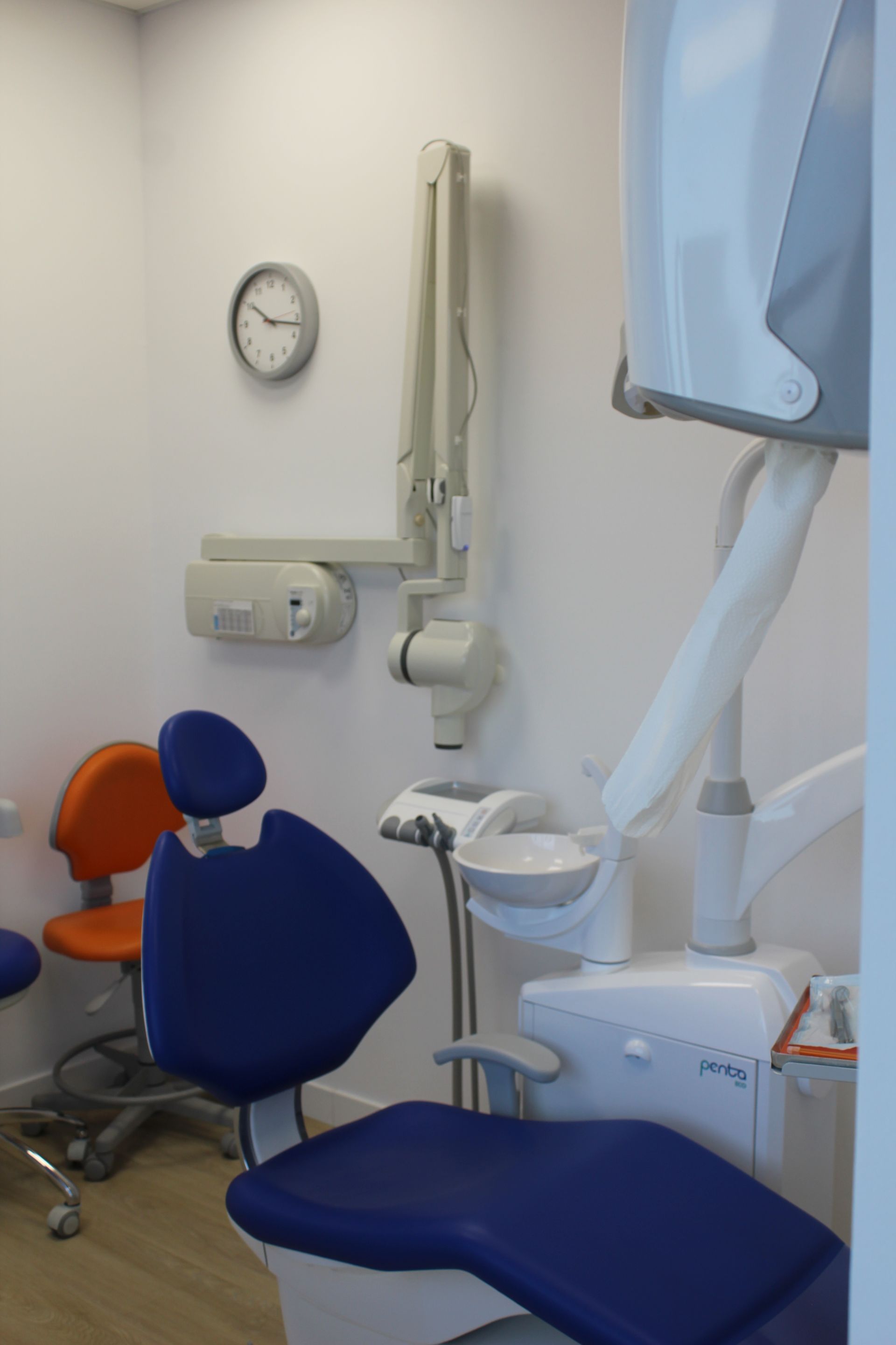Un consultorio dental con sillas azules y un reloj en la pared.