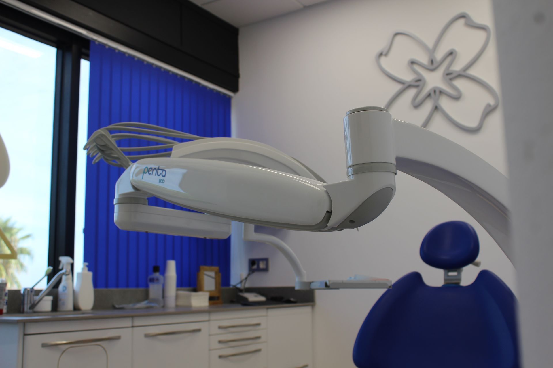 Una silla dental en un consultorio dental con una flor en la pared.