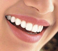 Un primer plano de la sonrisa de una mujer con dientes blancos y labios rosados.