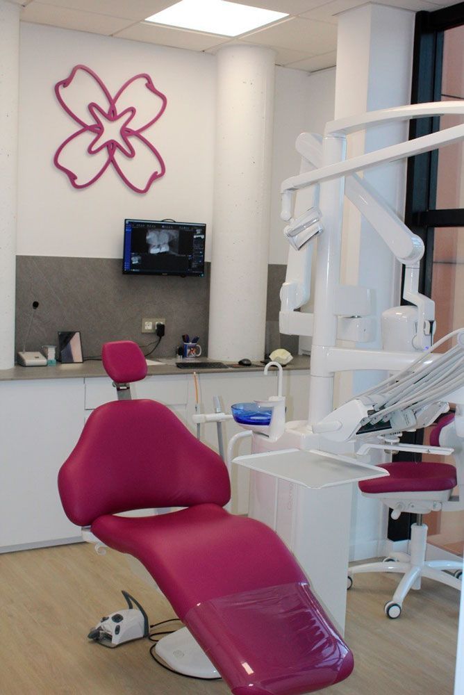 Un consultorio dental con una silla rosa y una flor en la pared.