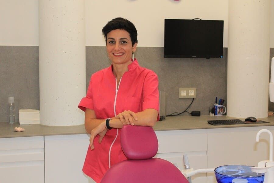 Una mujer con un uniforme rosa está de pie en una silla dental.