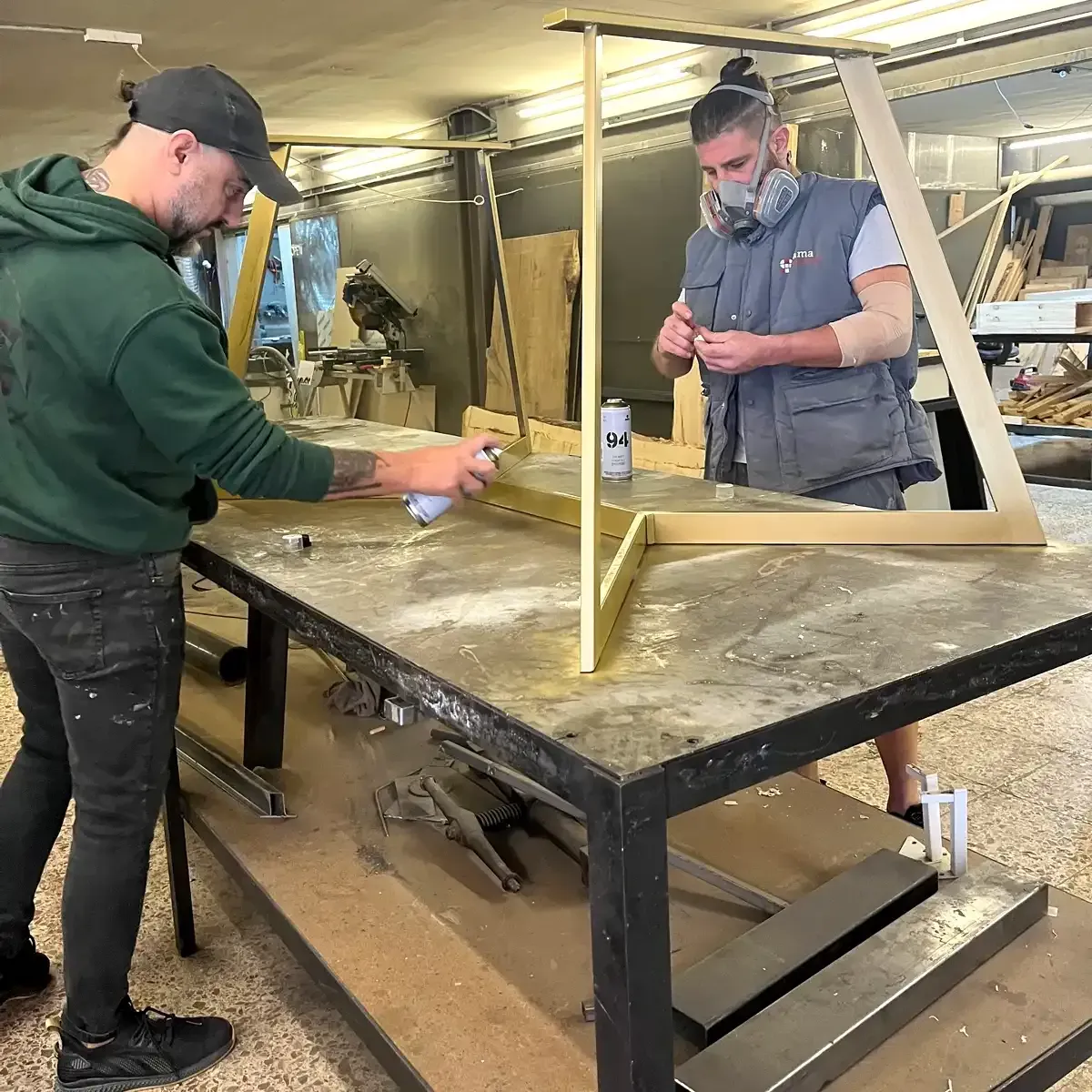 Dos hombres ensamblando un marco de madera en un banco de trabajo de un taller.