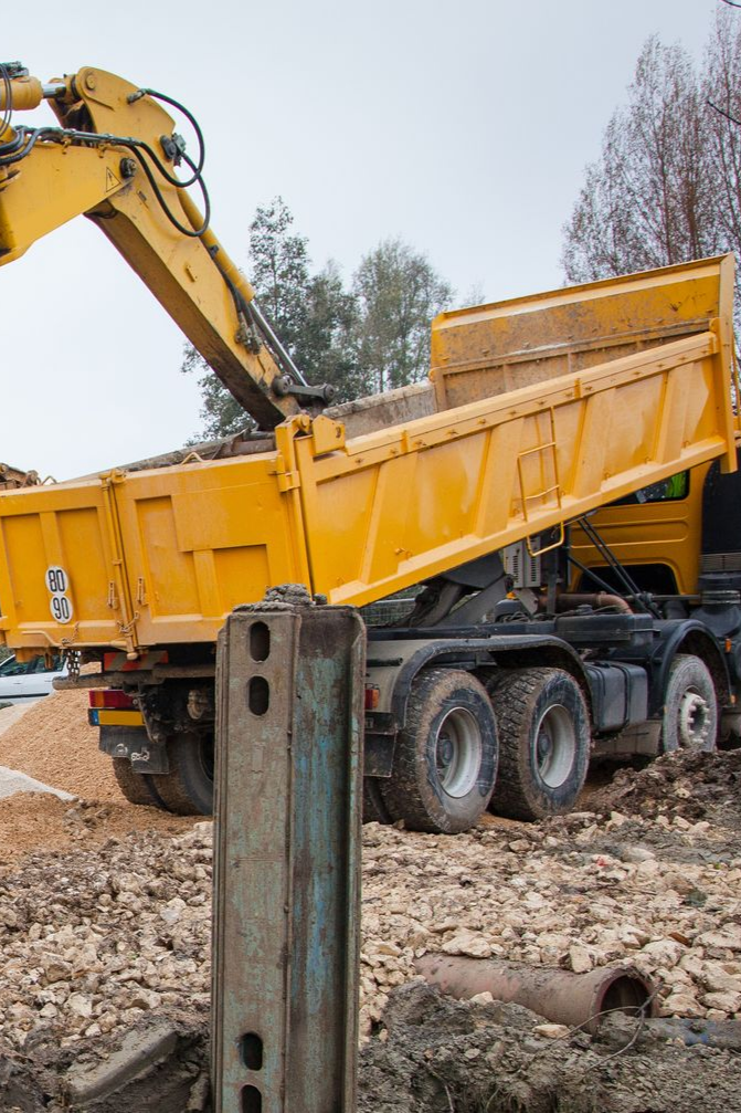 Une pelle mécanique jaune charge de la terre dans un camion-benne jaune sur un chantier de construction