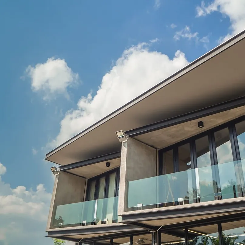 Una casa moderna con balcón y un cielo azul al fondo.