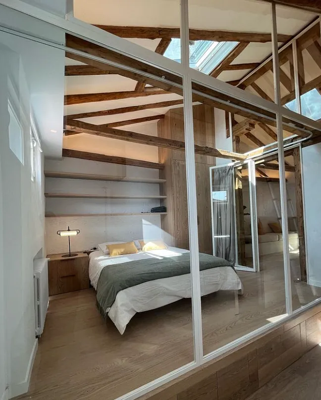 Un dormitorio con una cama detrás de una pared de cristal.