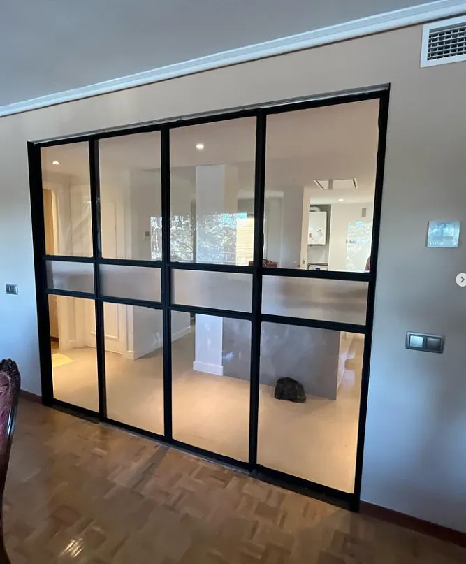 Una habitación con una puerta corrediza de vidrio entre dos habitaciones.