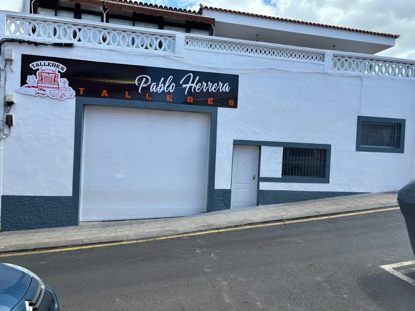 Un edificio blanco con puerta de garaje y un letrero que dice 