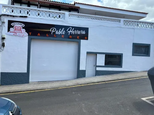 Un edificio blanco con puerta de garaje y un letrero que dice