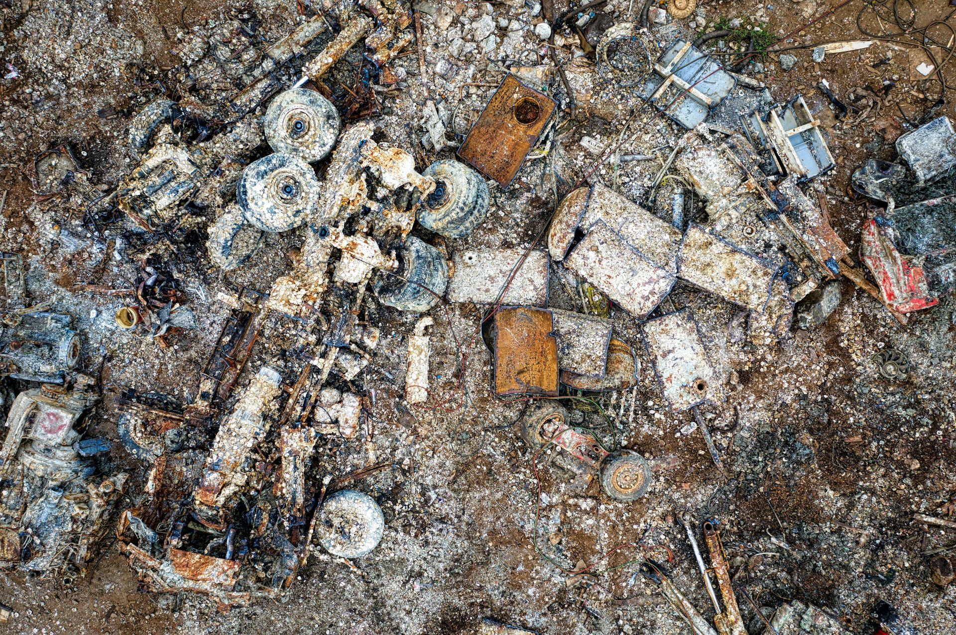 Vista aérea de escombros quemados y restos de metal carbonizado, incluyendo varios objetos circulares